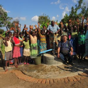 Group of villagers and Jim stand for photo in front of new shallow well