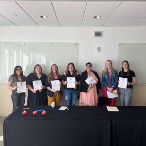 Students hold their honor society certificates, smiling