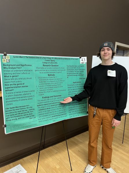Coehen Sperry poses in front of his research poster at the CURC showcase
