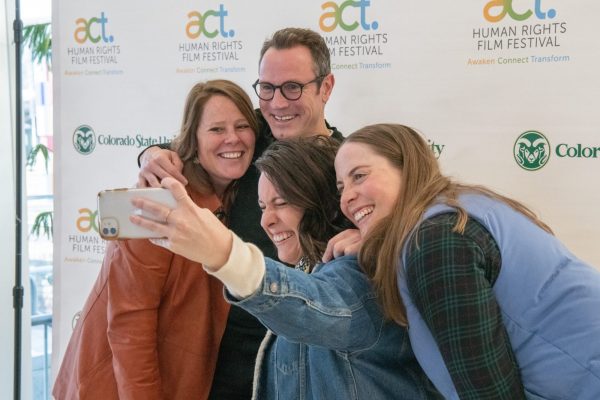 ACT Film Festival patrons take a selfie in front of a white banner for the festival.