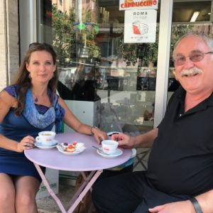 Two people sit outside drinking coffee together