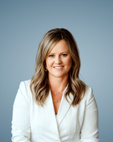 Headshot of Annika Boravansky in a white blazer against a blue background