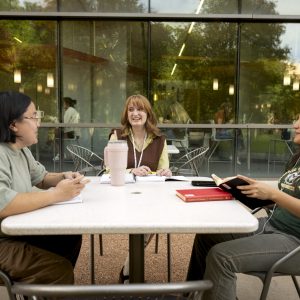 Three students in conversation at a table outside the BSB on the CSU campus