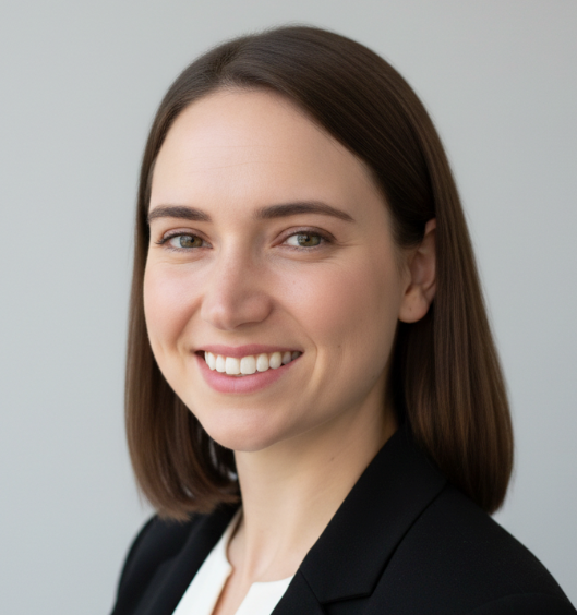 Headshot of Erin Carey wearing black blazer against a grey background. 