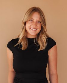 Headshot of Emilie Leazier wearing all black against a tan backdrop