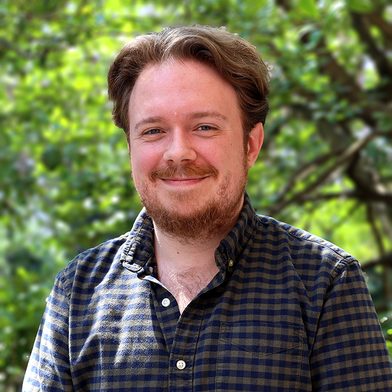 Headshot of Brandon Colvin outside in a dark checkered button up shirt